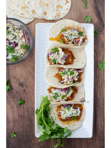 BBQ chicken tacos on a white plate and a dark wood background