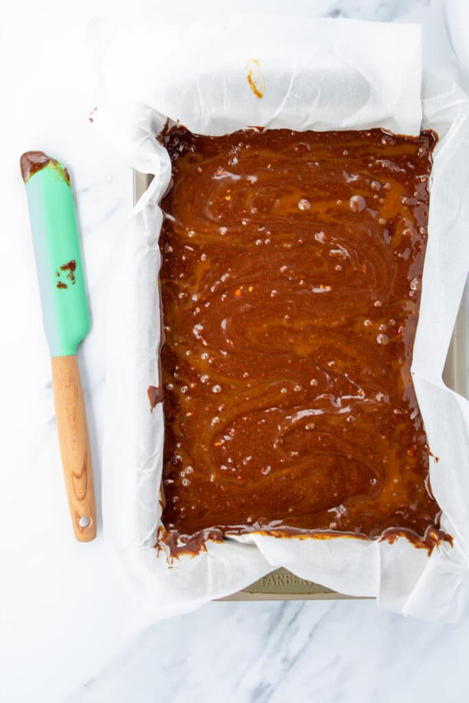 brownies in a pan before baking with caramel swirl