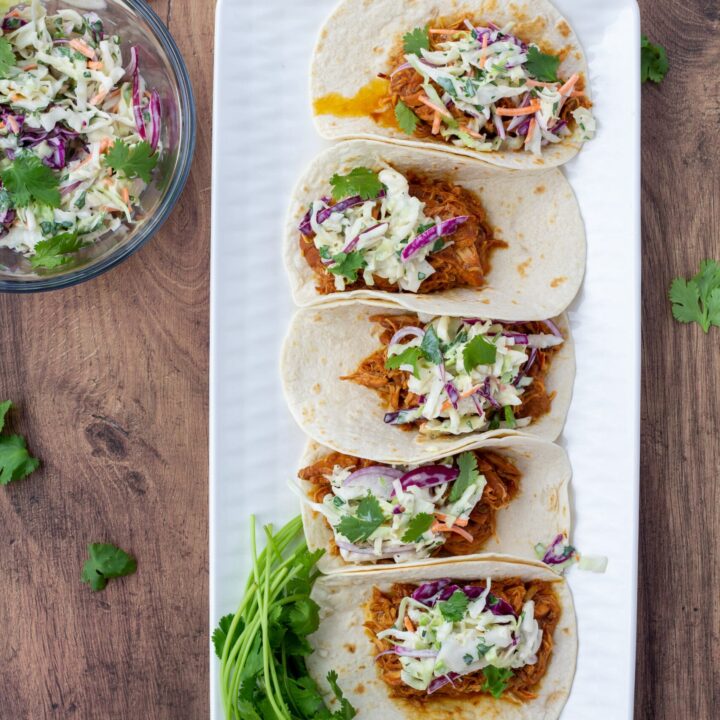 chicken tacos on a white plate and a wood background