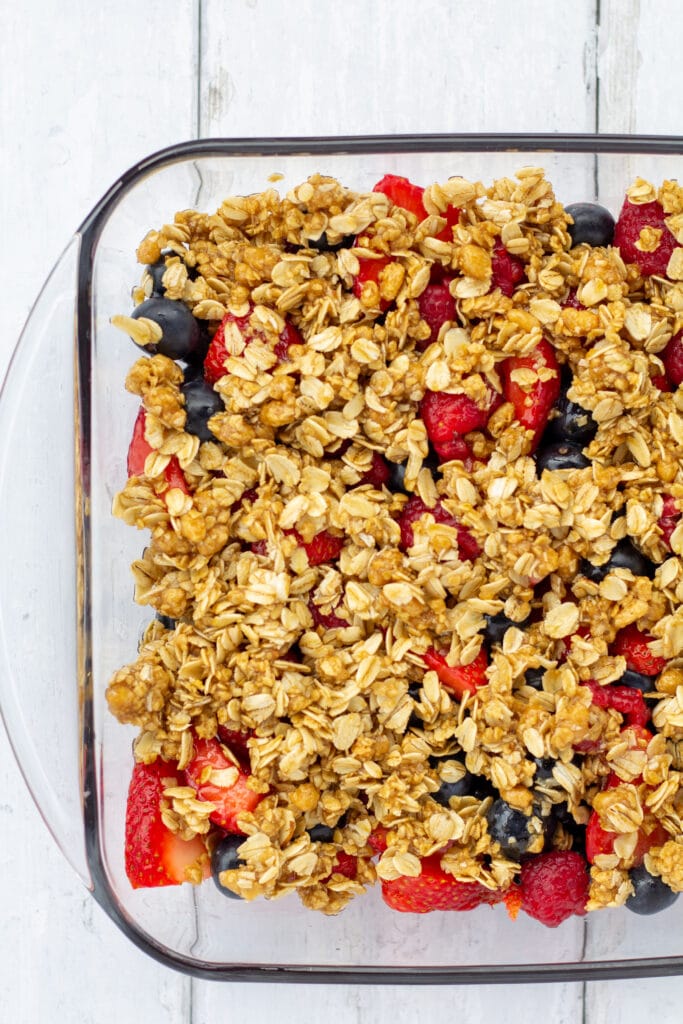 fruit crisp with oat topping on a white background