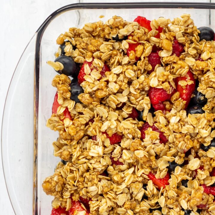 fruit in a glass pan with oat topping on a white background