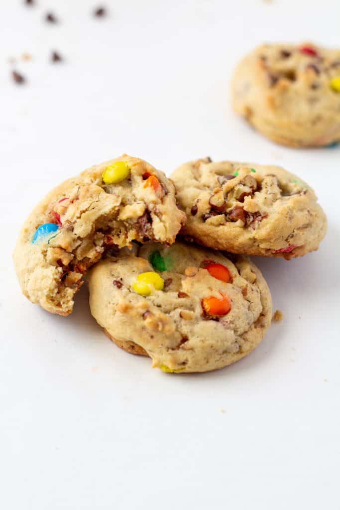 4 chocolate chip cookies with one bite taken out on a white background