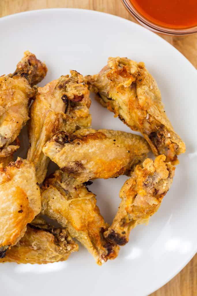 air fried chicken wings on a white plate with sauce on the sides