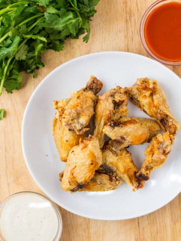 chicken wings on a white plate with sauces