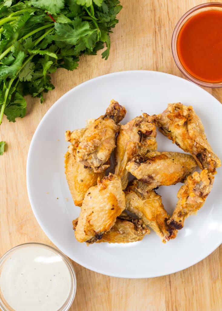 chicken wings on a white plate with sauces 