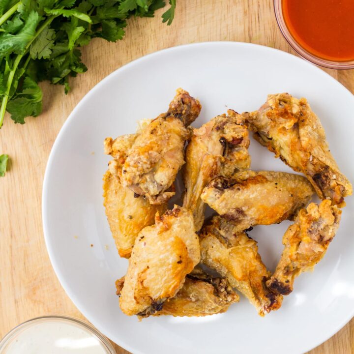 chicken wings on a white plate with sauces