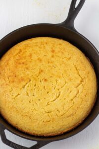 cornbread in a cast iron skillet on a white background