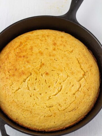 cornbread in a cast iron skillet on a white background