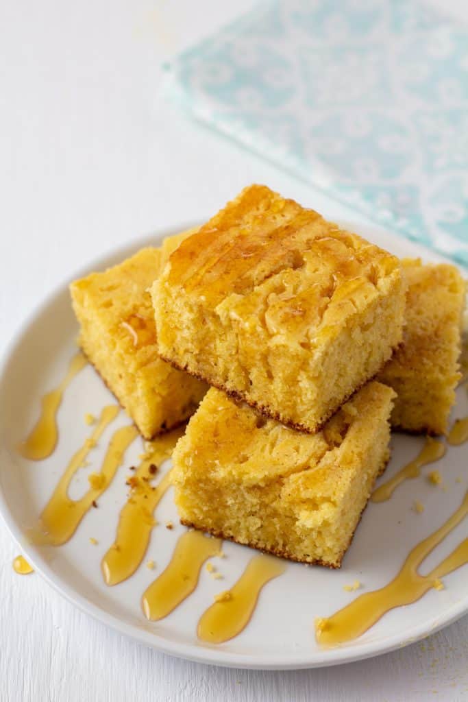 skillet cornbread drizzled in honey on a white plate