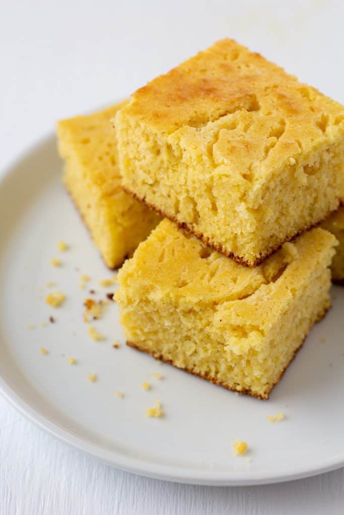 stacked cornbread pieces on a white plate