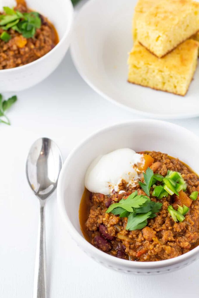 pumpkin chili in a white bowl with a spoon on the side. 