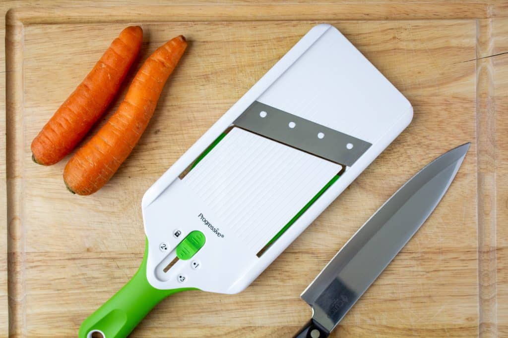 mandoline, carrots, chef knife, on cutting board