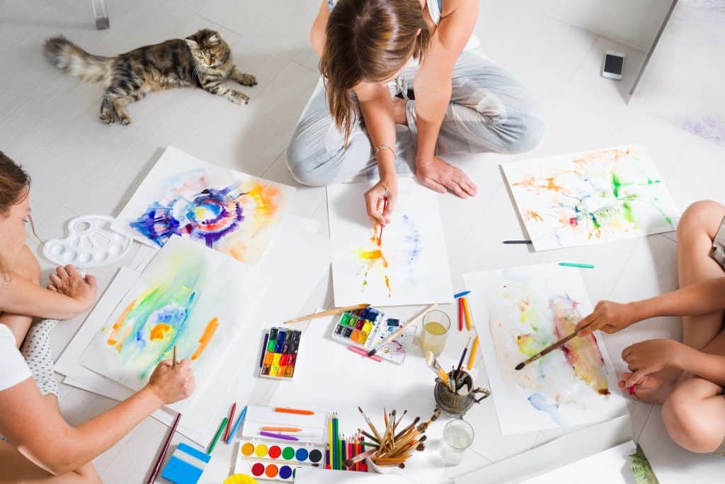 kids painting on a white floor during their time at home 