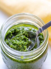 pesto in a jar on a white background with a spoon