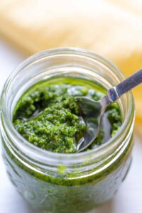 pesto in a jar on a white background with a spoon