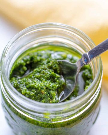 pesto in a jar on a white background with a spoon