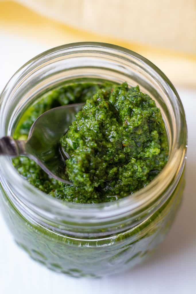 pesto in a jar on a white background with a spoon