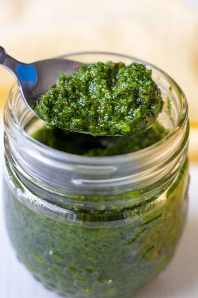 pesto in a jar on a white background with a spoon