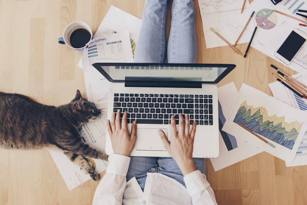 woman working on a computer sitting on the ground while spending time at home 