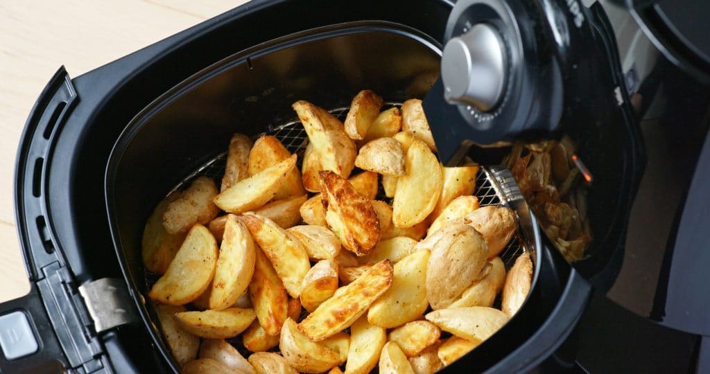 toasted potato wedges in the basket of an air fryer