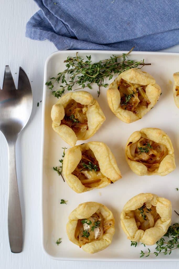 puff pasty bites on a white plate framed by thyme and a metal fork