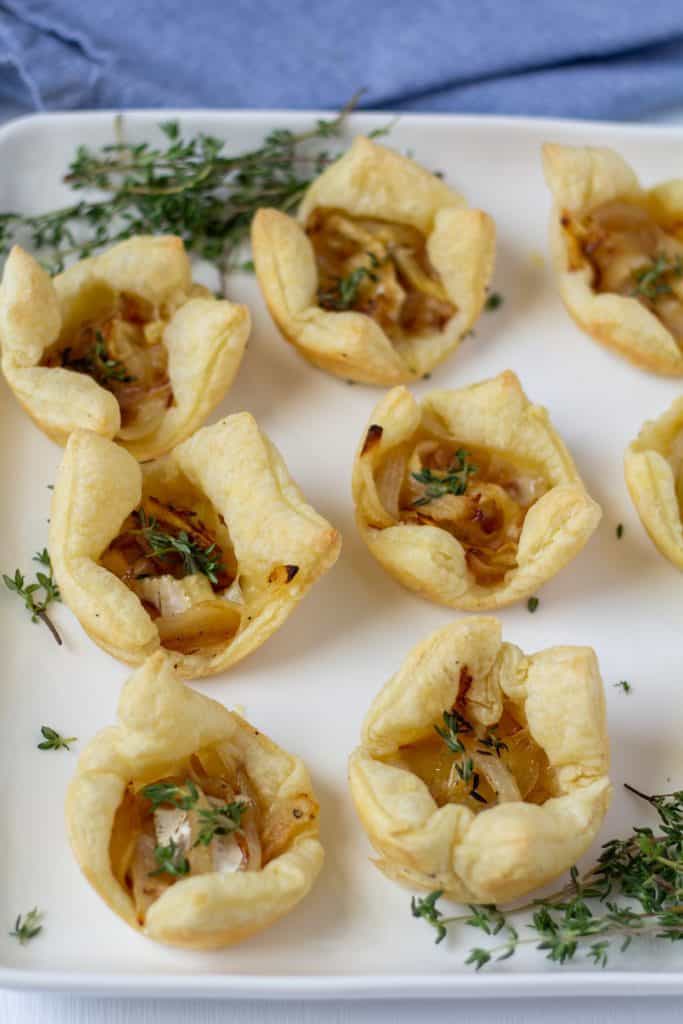 puff pasty bites on a white plate framed by thyme