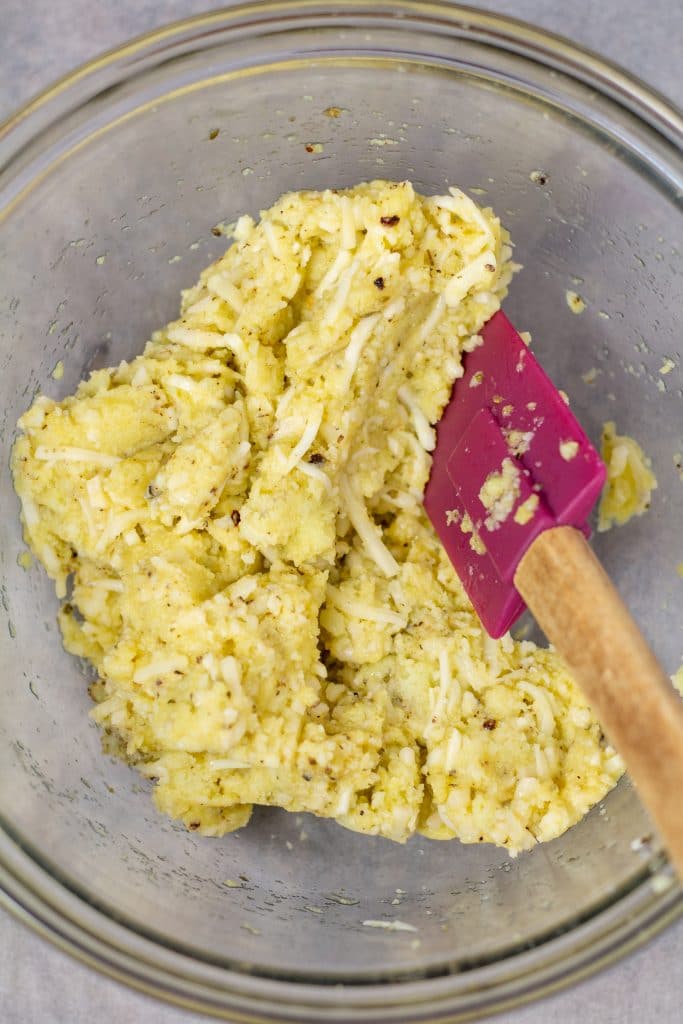 cauliflower rice mixture in a glass bowl with a pink spatula