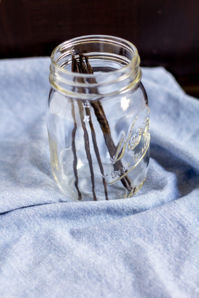 vanilla beans in a clear mason jar on a blue background