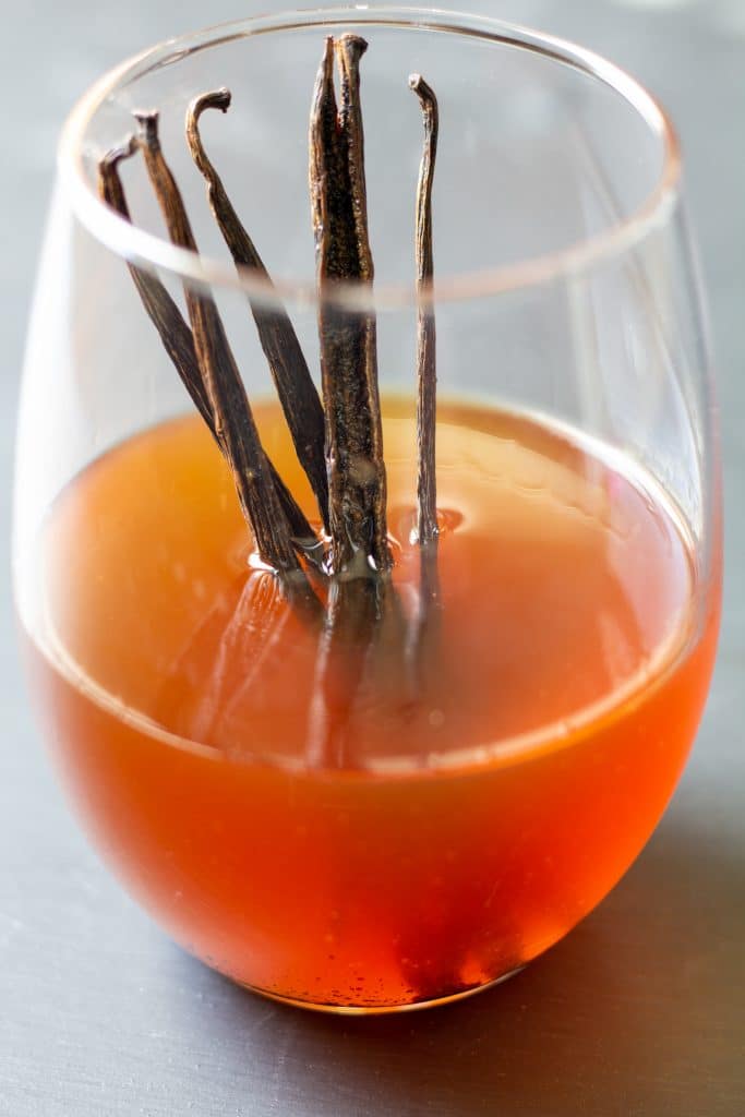 vanilla extract in a clear glass with vanilla beans standing up