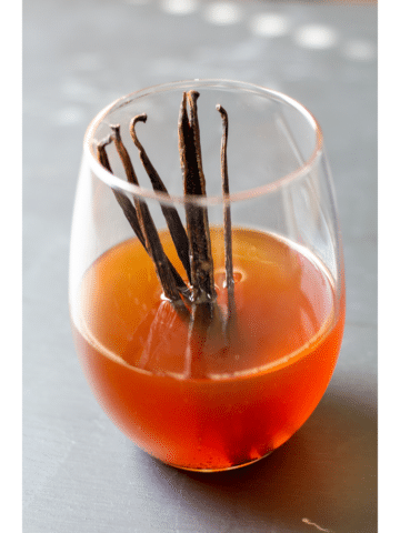 vanilla extract in a clear glass with vanilla beans standing up