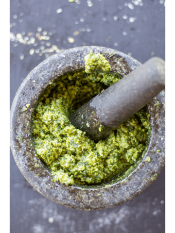 pesto mixed in a mortar and pestle on a black background