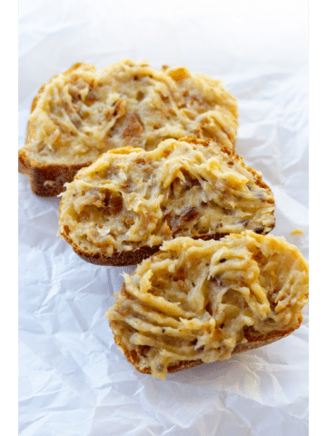 three pieces of bread with roasted garlic spread over the tops on a white background