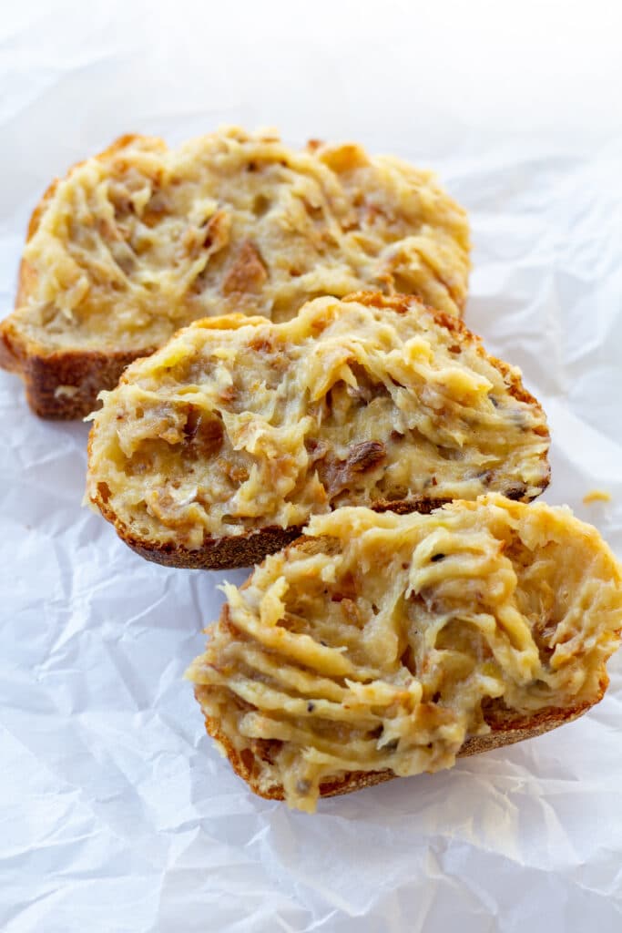 three pieces of bread with roasted garlic spread over the tops on a white background