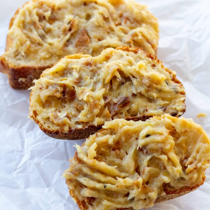 three pieces of bread with roasted garlic spread over the tops on a white background