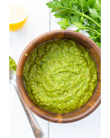 green sauce in a wooden bowl with a spoon on the side