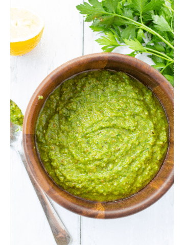 green sauce in a wooden bowl with a spoon on the side