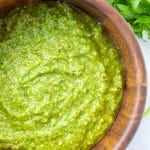 green sauce in a wooden bowl on a white background