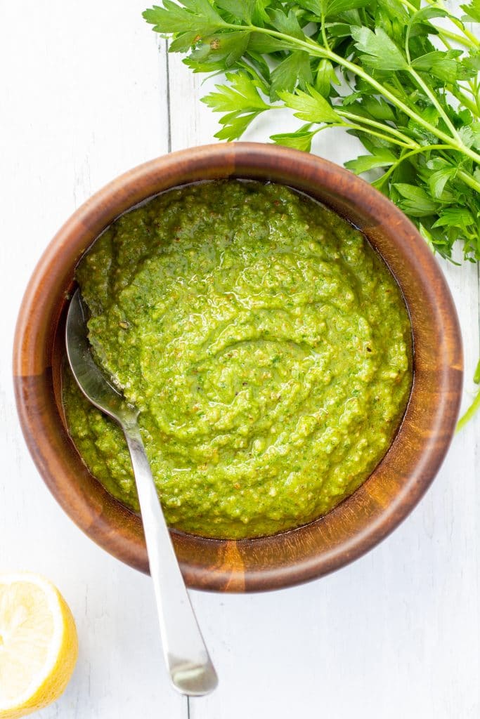 Green sauce with spoon in a wooden bowl