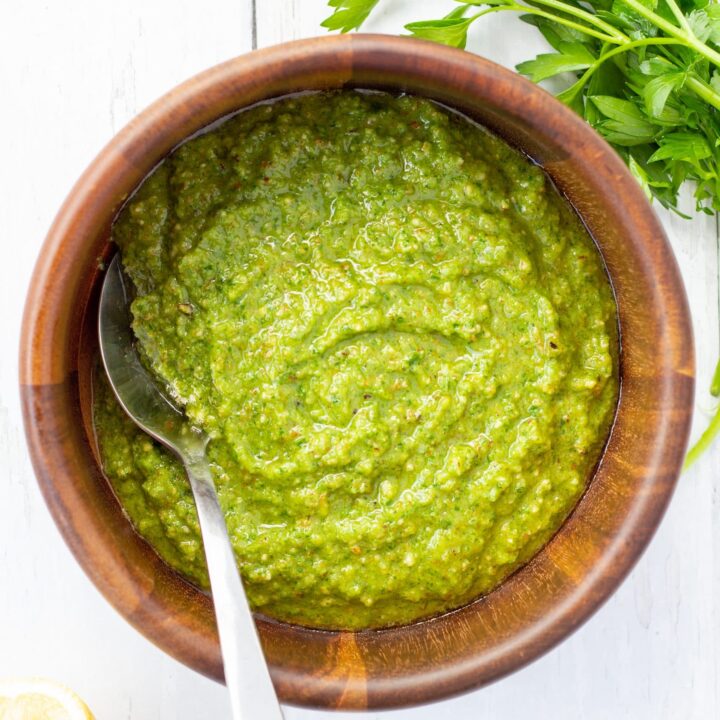 Green sauce with spoon in a wooden bowl