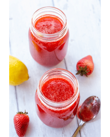 strawberry jam in jars on a white background with lemons and strawberries on the side