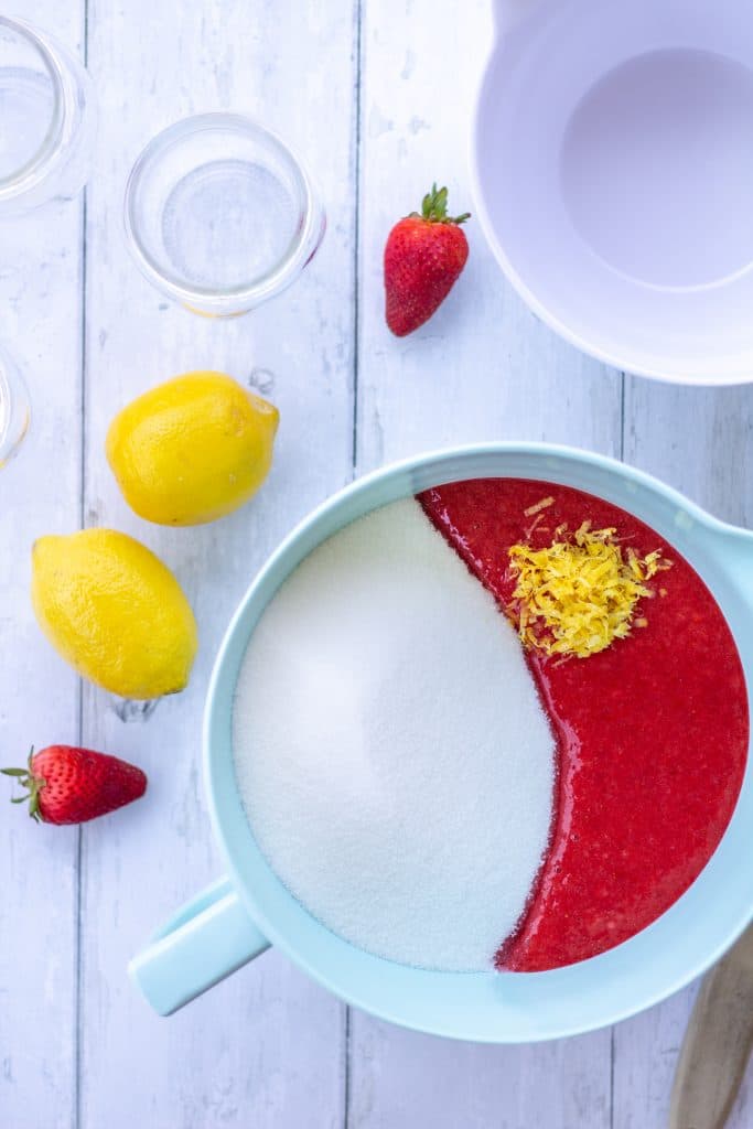strawberries, sugar, and lemon zest in a bowl on a white background in bright light