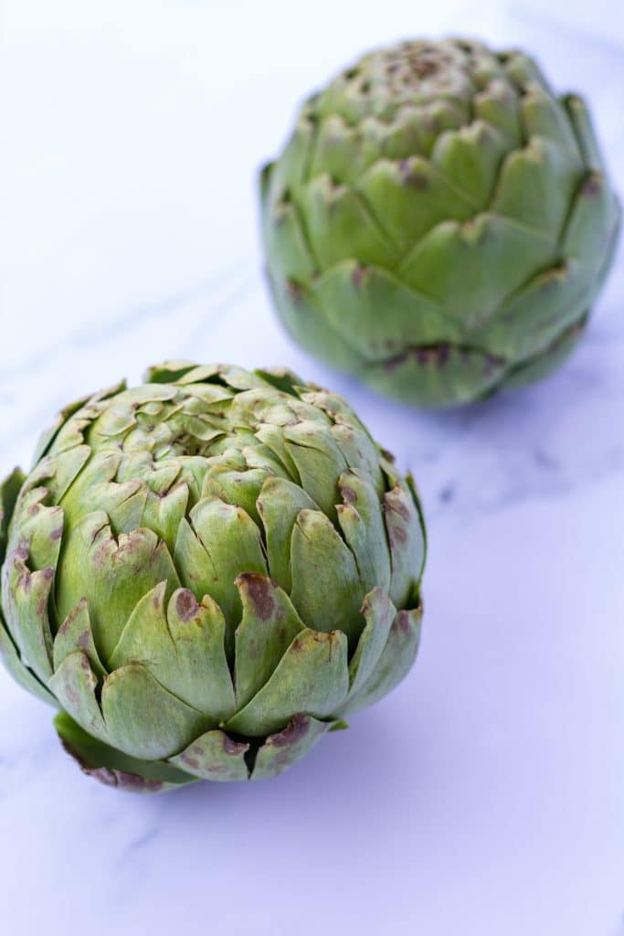 whole, unsnipped artichokes on a counter