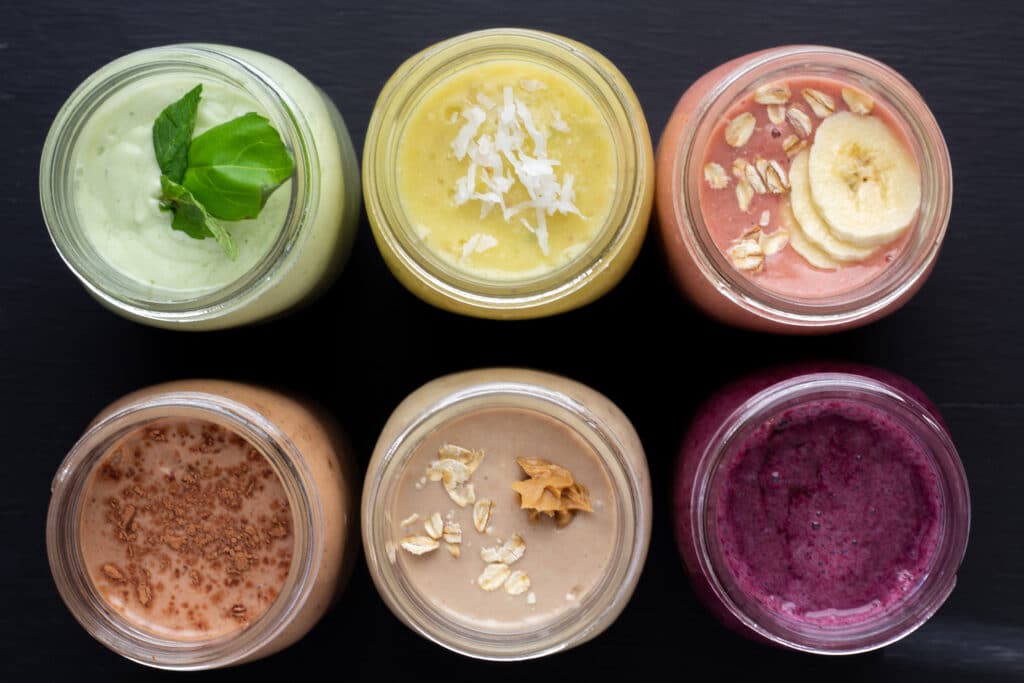 overhead view of six smoothies lined up on a black background