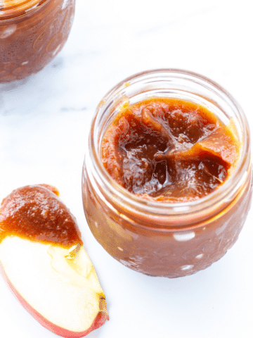 a-close-up-of-the-top-of-apple-butter-in-a-glass-jar-on-a-white-counter