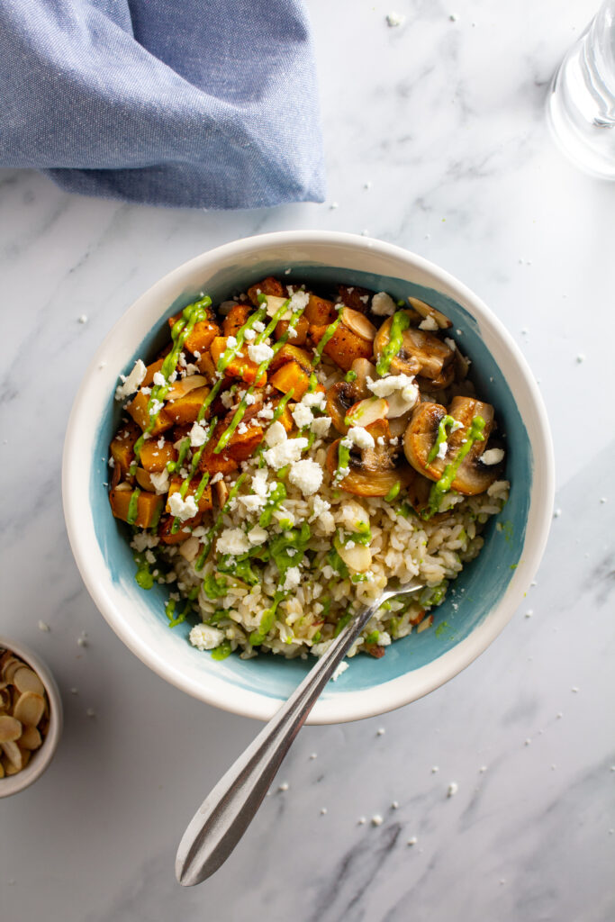 Feature photo of a bowl with vegetables, rice, and sauce on a white marble background