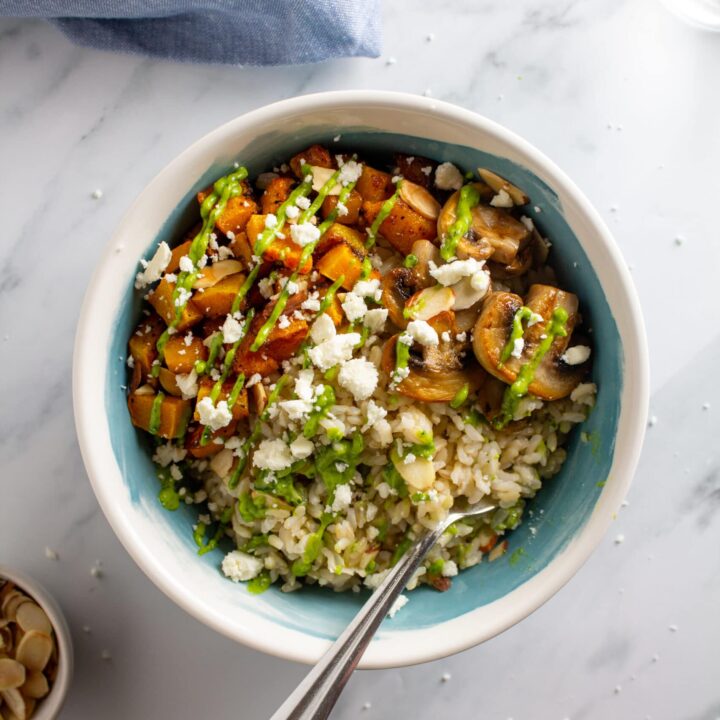 Feature photo of a bowl with vegetables, rice, and sauce on a white marble background