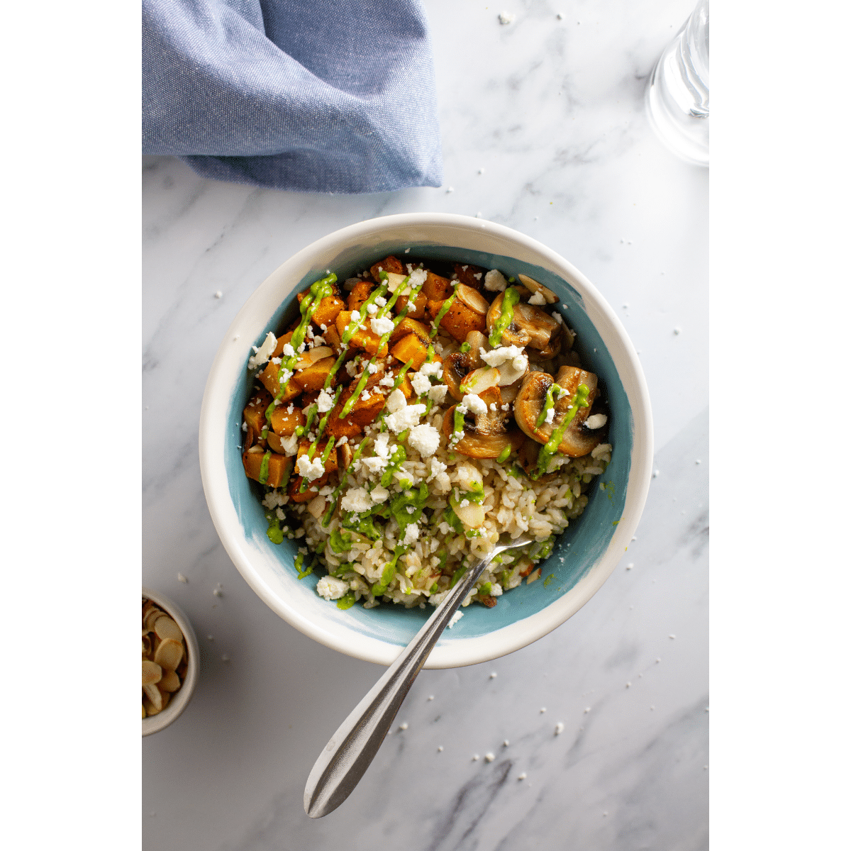 Feature photo of a bowl with vegetables, rice, and sauce on a white marble background