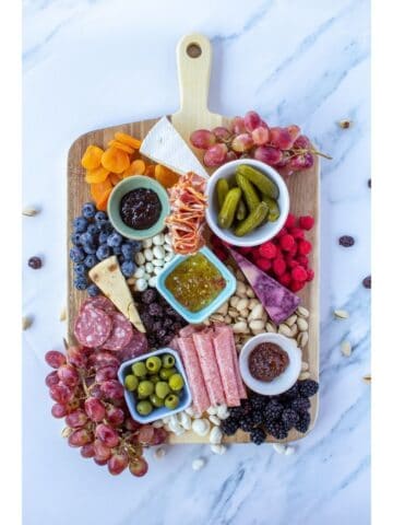 a wooden board filled with cheese, meats, and other snacks