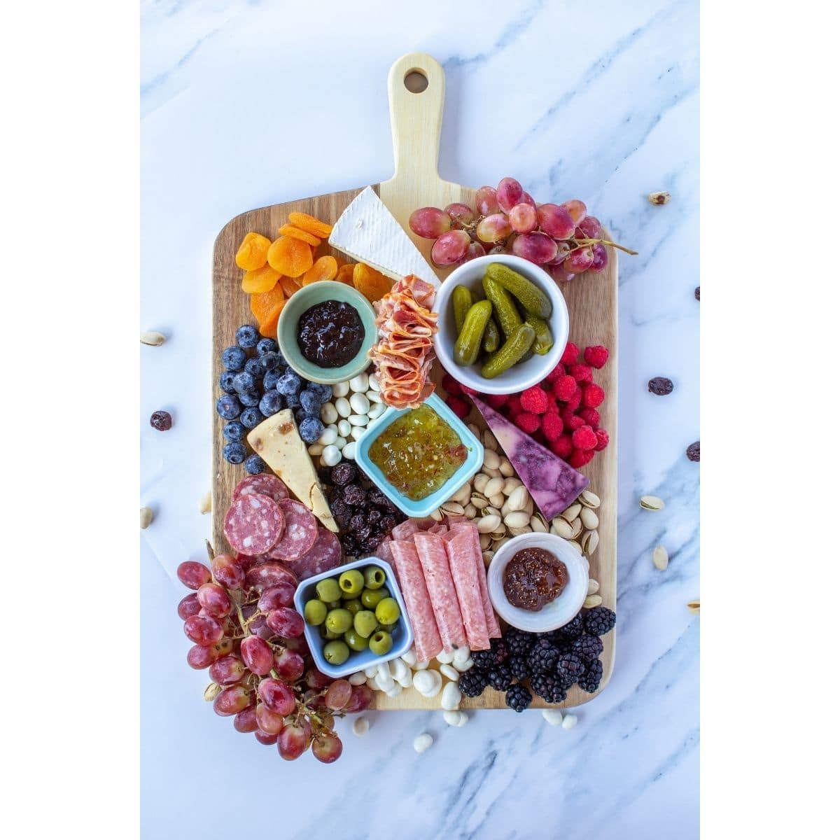 a wooden board filled with cheese, meats, and other snacks