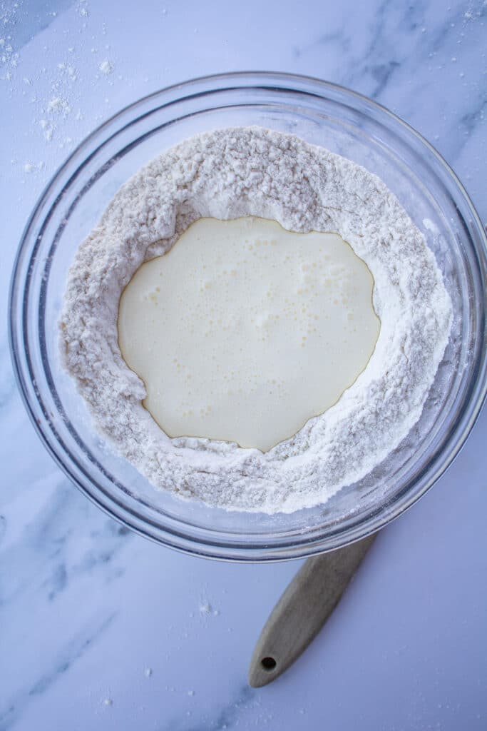 Flour and cream in a bowl on a white marble surface